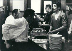 „Wirtsleute hinter der Theke bei der Arbeit, Frankfurt, ca. 1960er-Jahre“